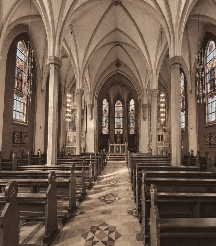 A church interior seen from a pew, with figures in the stained glass above.
